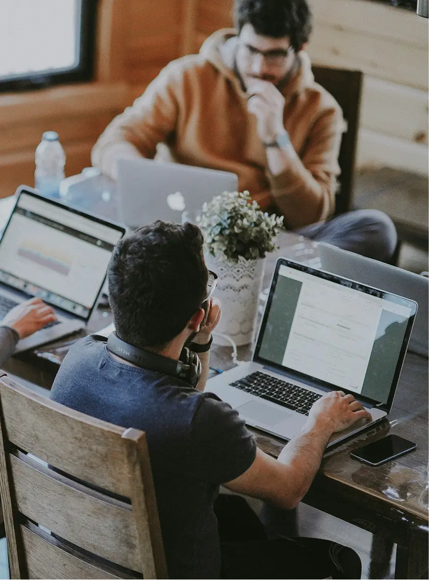 Trois consultants en stratégie digitale travaillent intensivement sur des ordinateurs portables dans un espace de coworking moderne à Bordeaux.