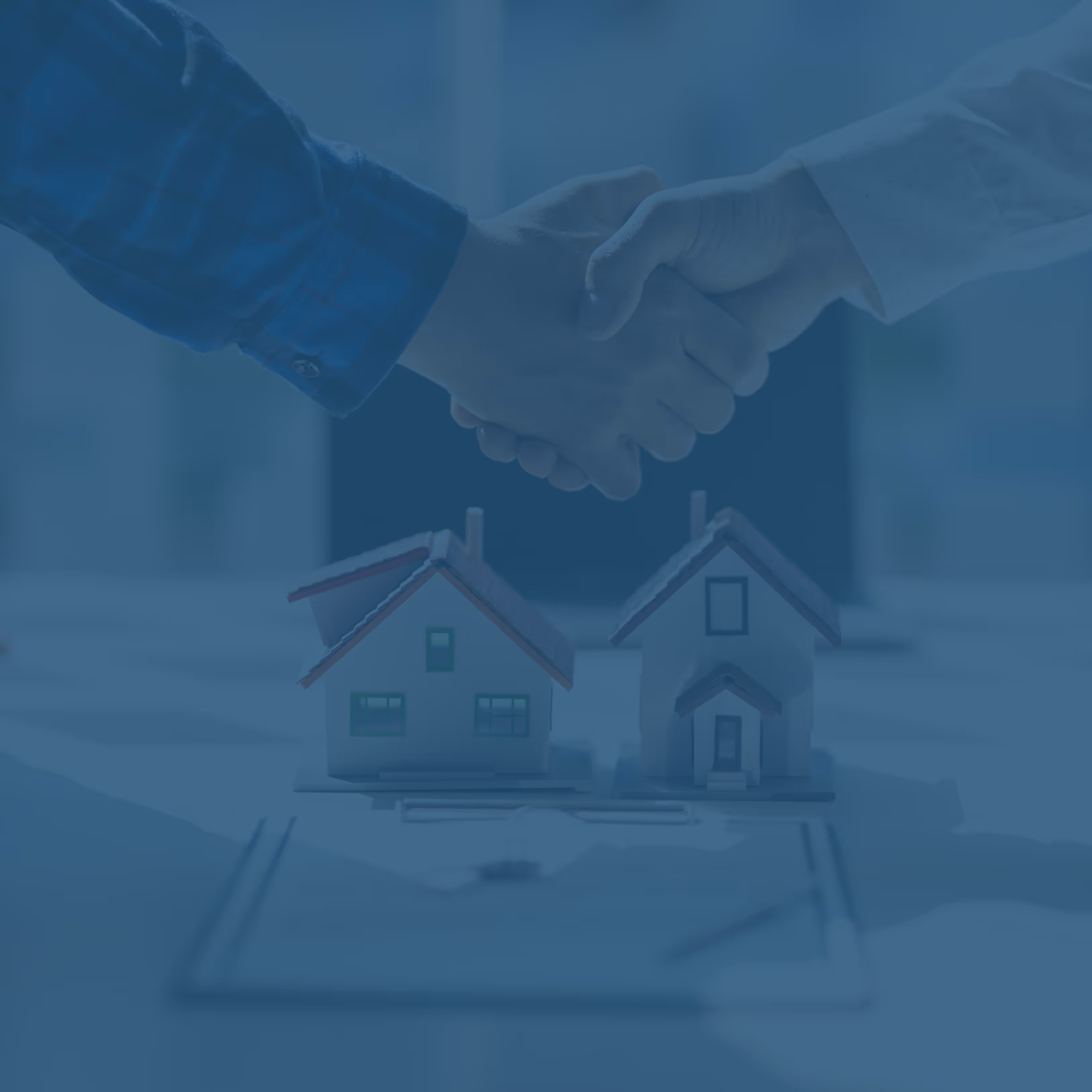 Two people shaking hands above a table with miniature house models and a floor plan.