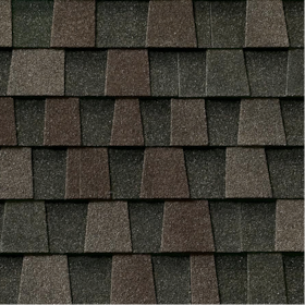 Close-up of asphalt roof shingles in dark gray and brown shades arranged in staggered rows.