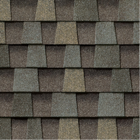 Close-up of textured asphalt roof shingles in shades of brown, gray, and tan arranged in a staggered pattern.