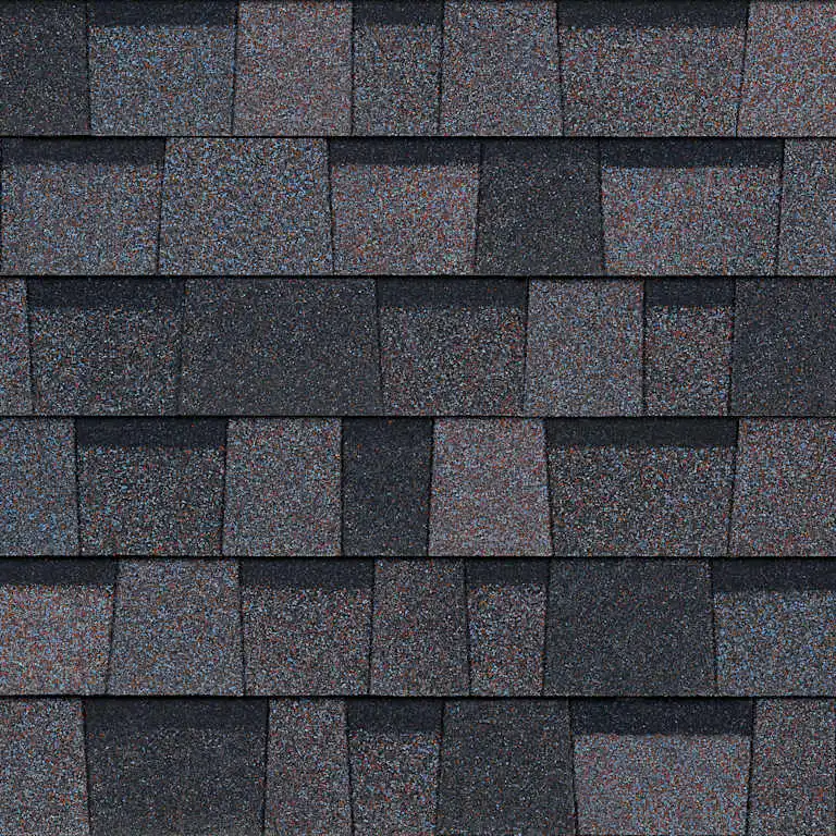 Close-up of layered asphalt roof shingles in mixed dark and muted purple tones.