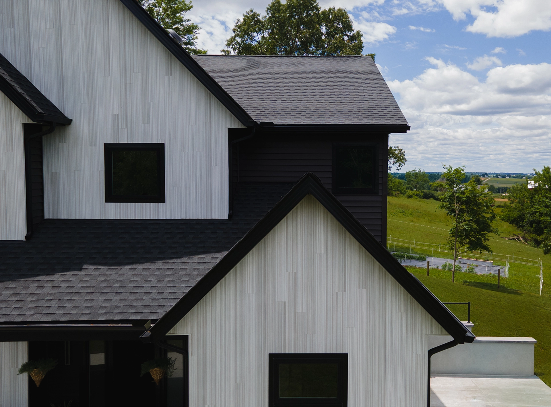 Close-up of a brown shingle roof with damaged and lifted shingles revealing underlying black layer.