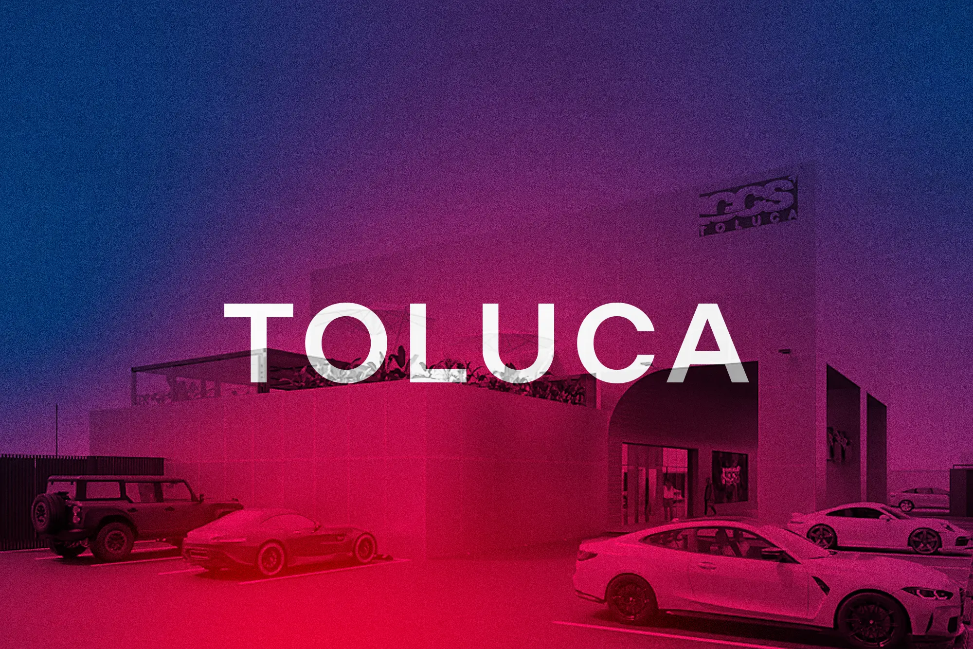Modern building with a sign reading 'CCS Toluca' and several parked cars in front under a blue and purple sky.