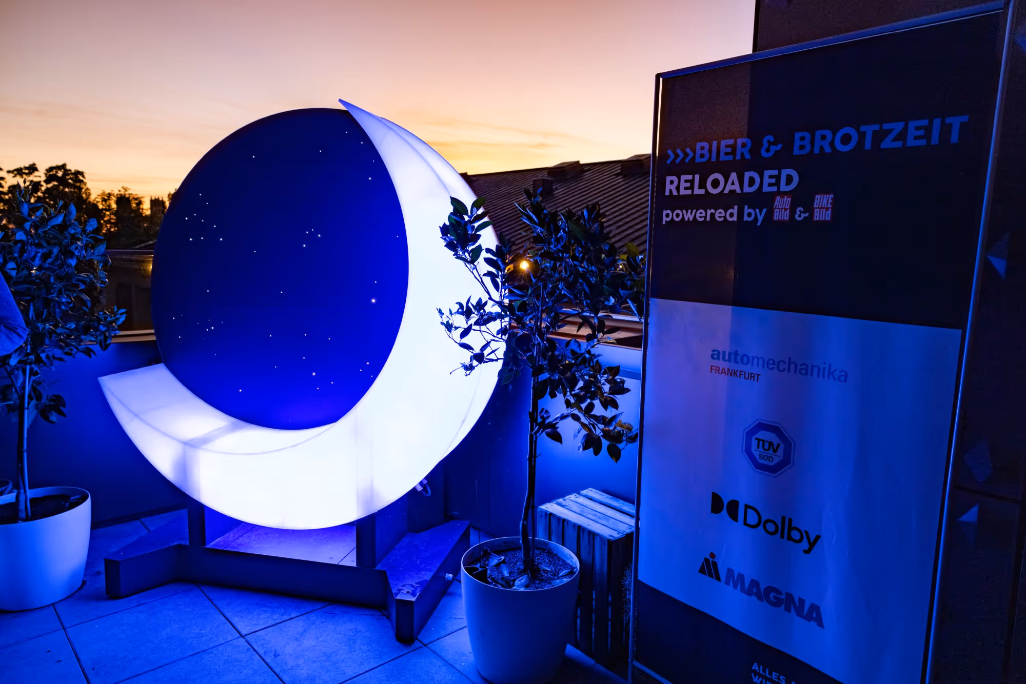 Eine halbrunde Lichtinstallation neben einem Banner der Sponsoren des Events.
