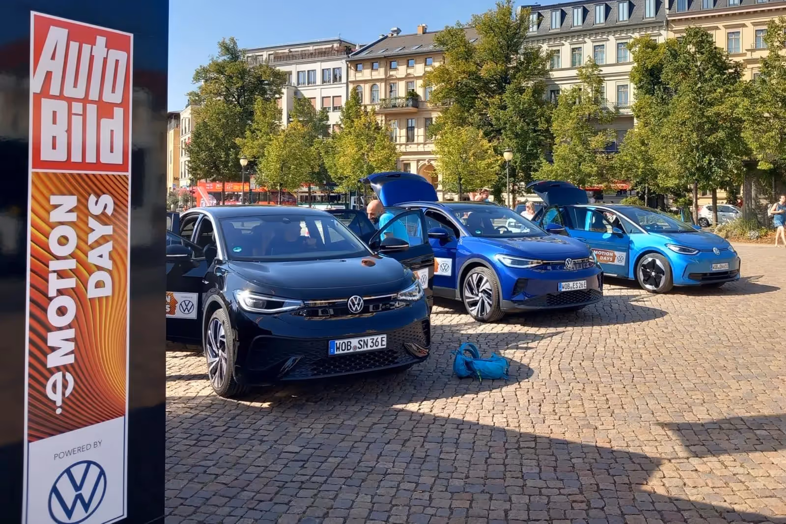 Drei blaue VWs stehen auf einem Platz, davor sieht man eine Säule der Auto Bild Emtion Days und VW.