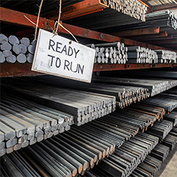 Metal racks full of raw bars and billets ready to be processed with a sign saying "Ready to Run"