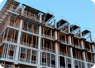 Partially constructed building with exposed framework and scaffolding against a clear blue sky, conveying progress and development in urban construction.