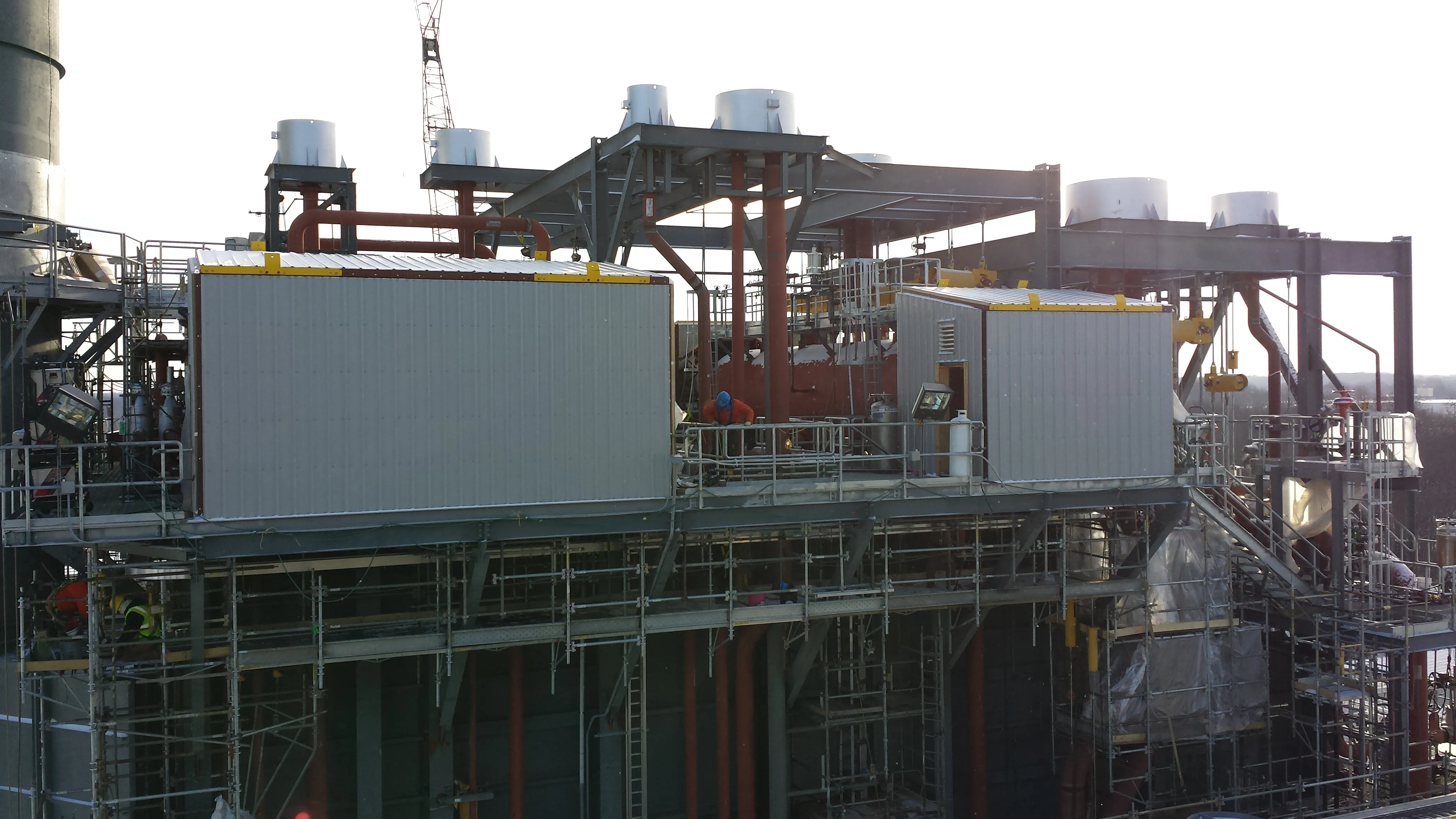 Industrial construction site with scaffolding, metal structures, and workers in safety gear.