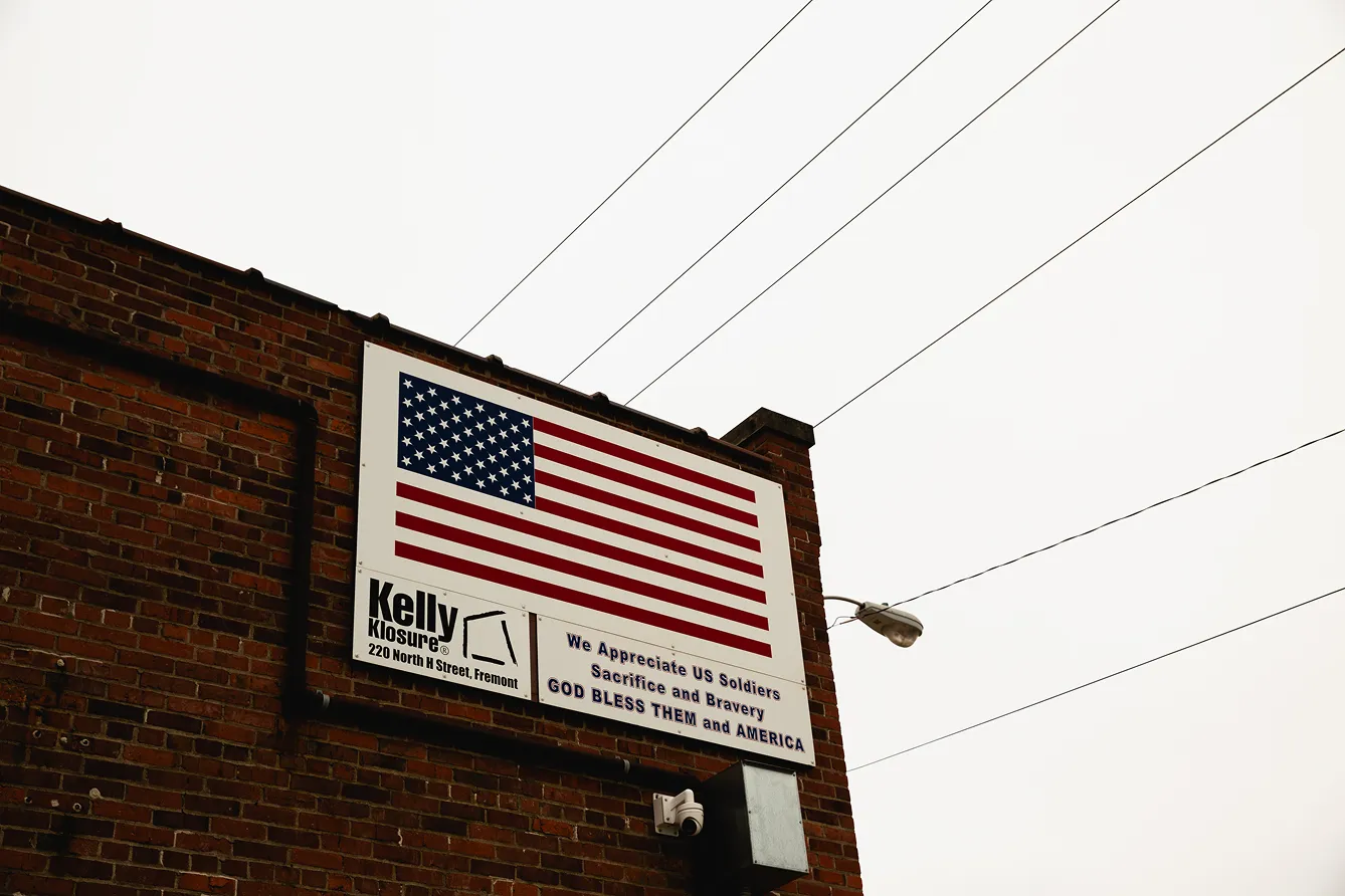 Sign on brick building with an American flag and text appreciating US soldiers for their sacrifice and bravery.