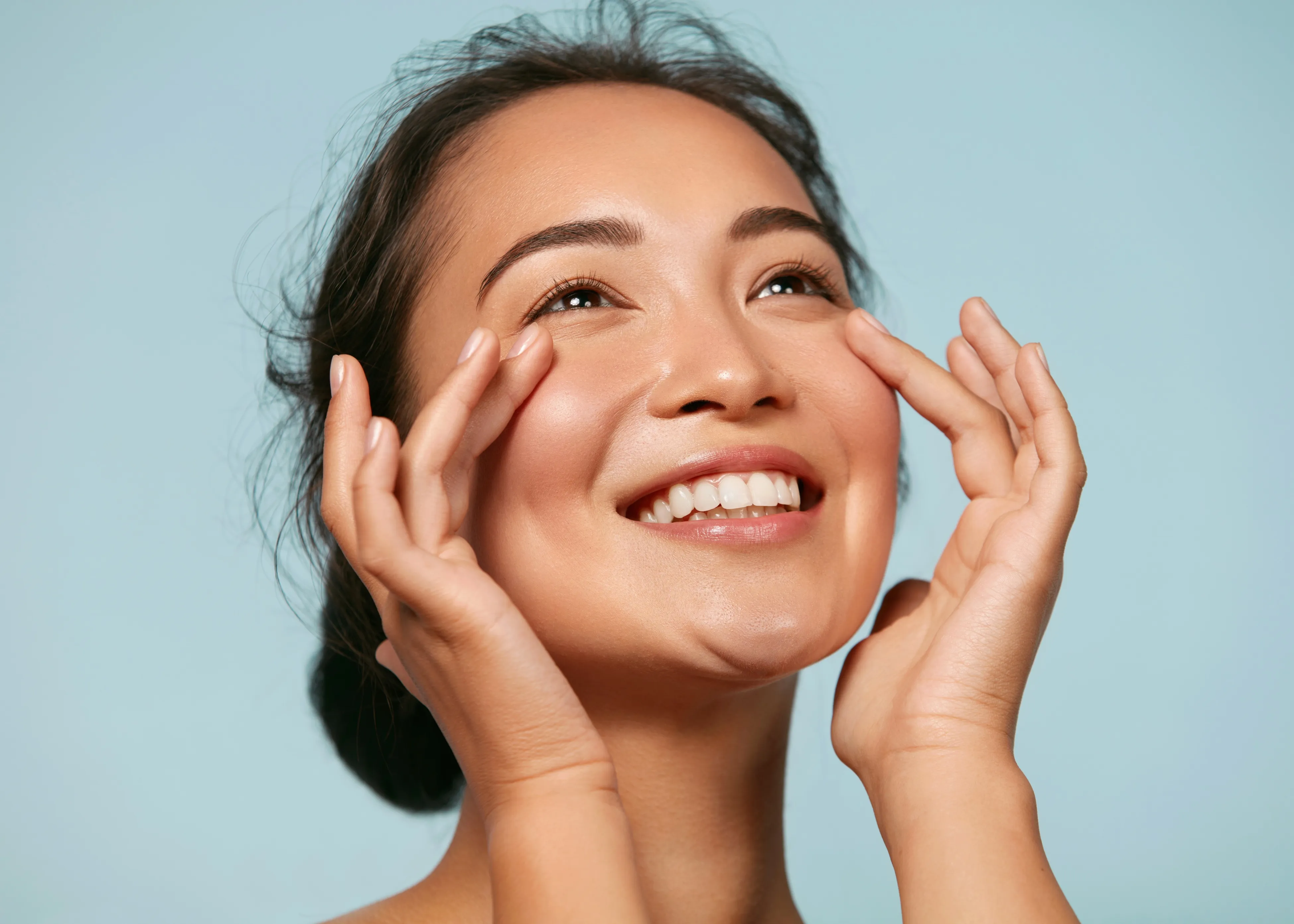 A woman smiling with her hands on her face.