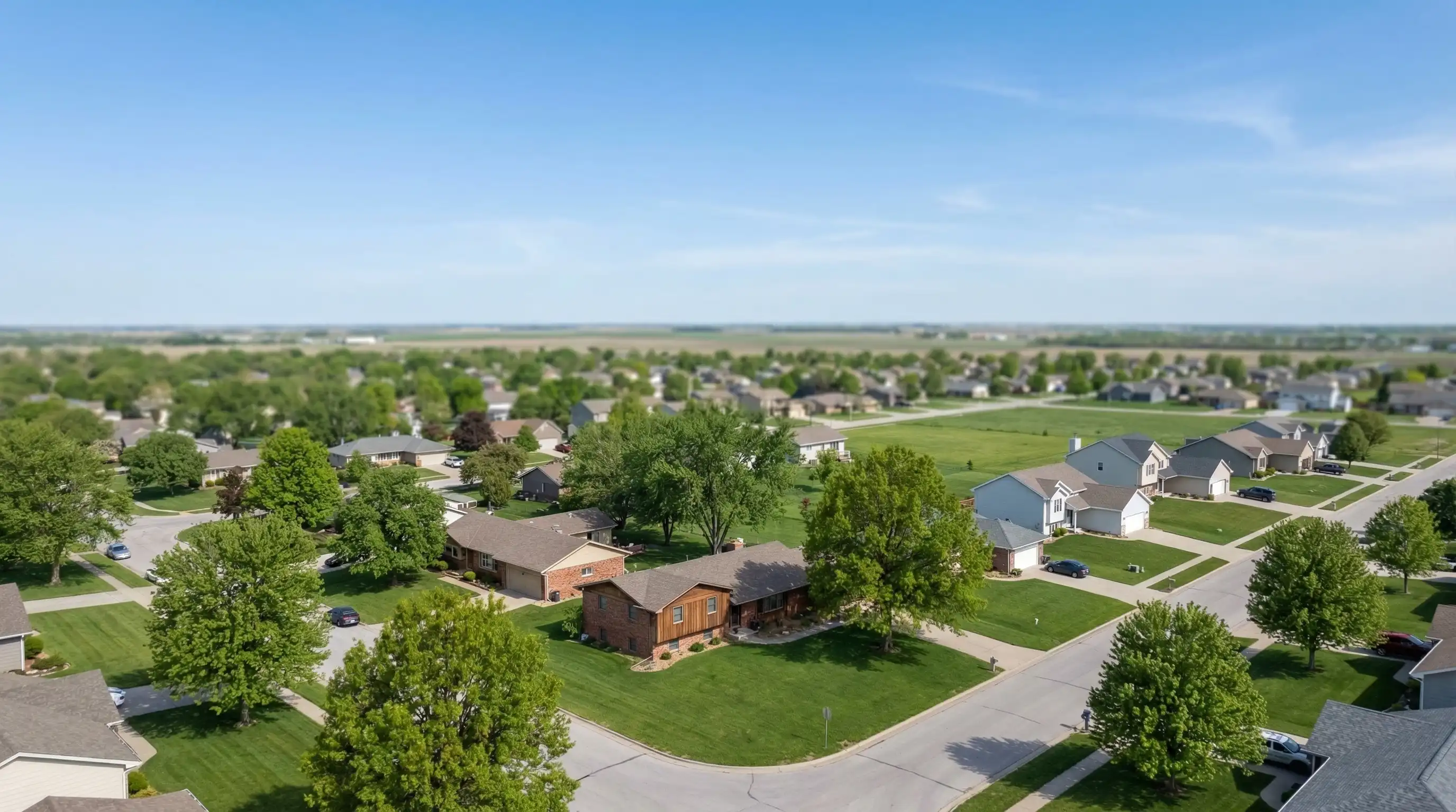 Real estate agent meeting with clients at the front door of a classic ranch home in a Lincoln, NE neighborhood with mature trees and spring greenery