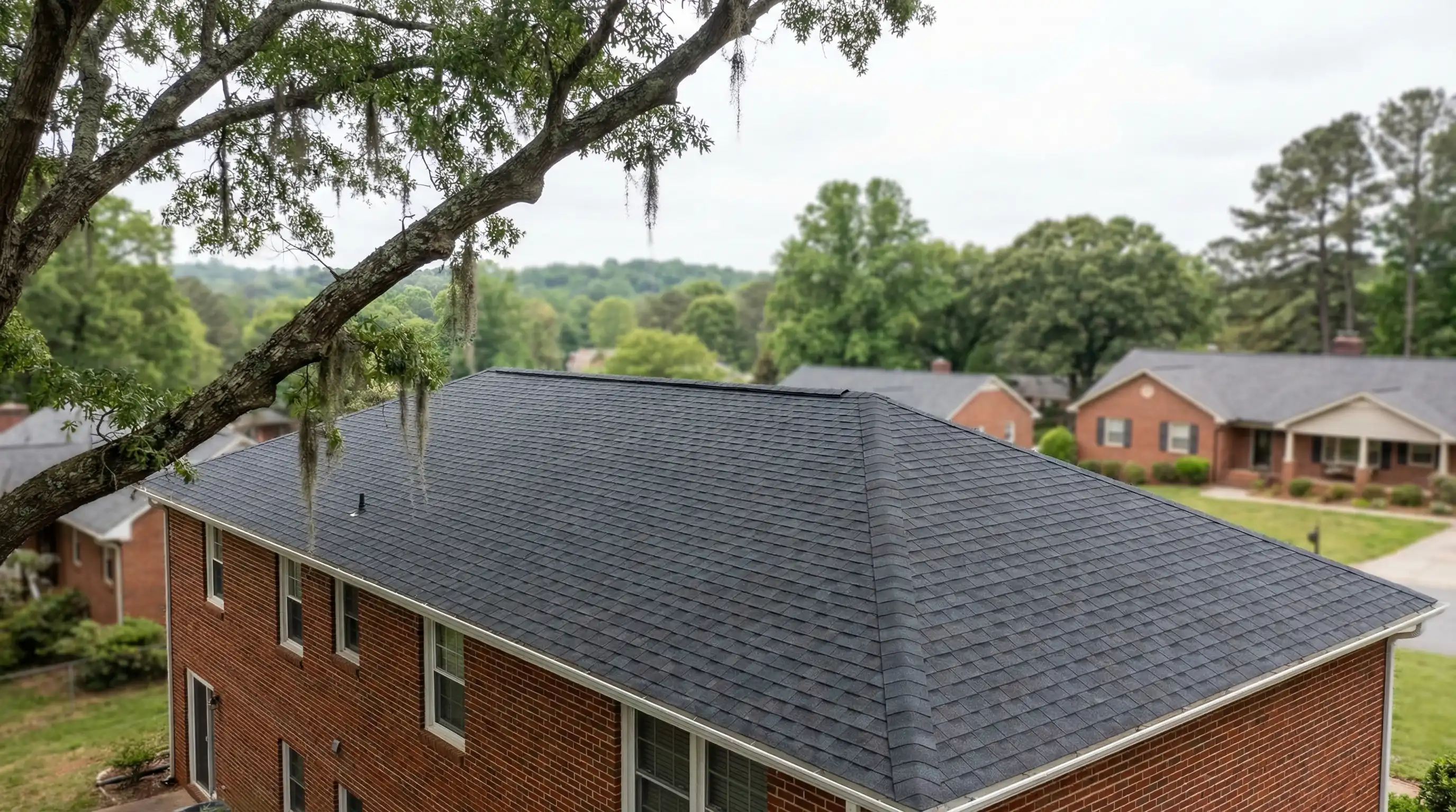 Roofing contractor installing architectural shingles on a two-story brick home in a Winston-Salem, NC neighborhood after storm damage