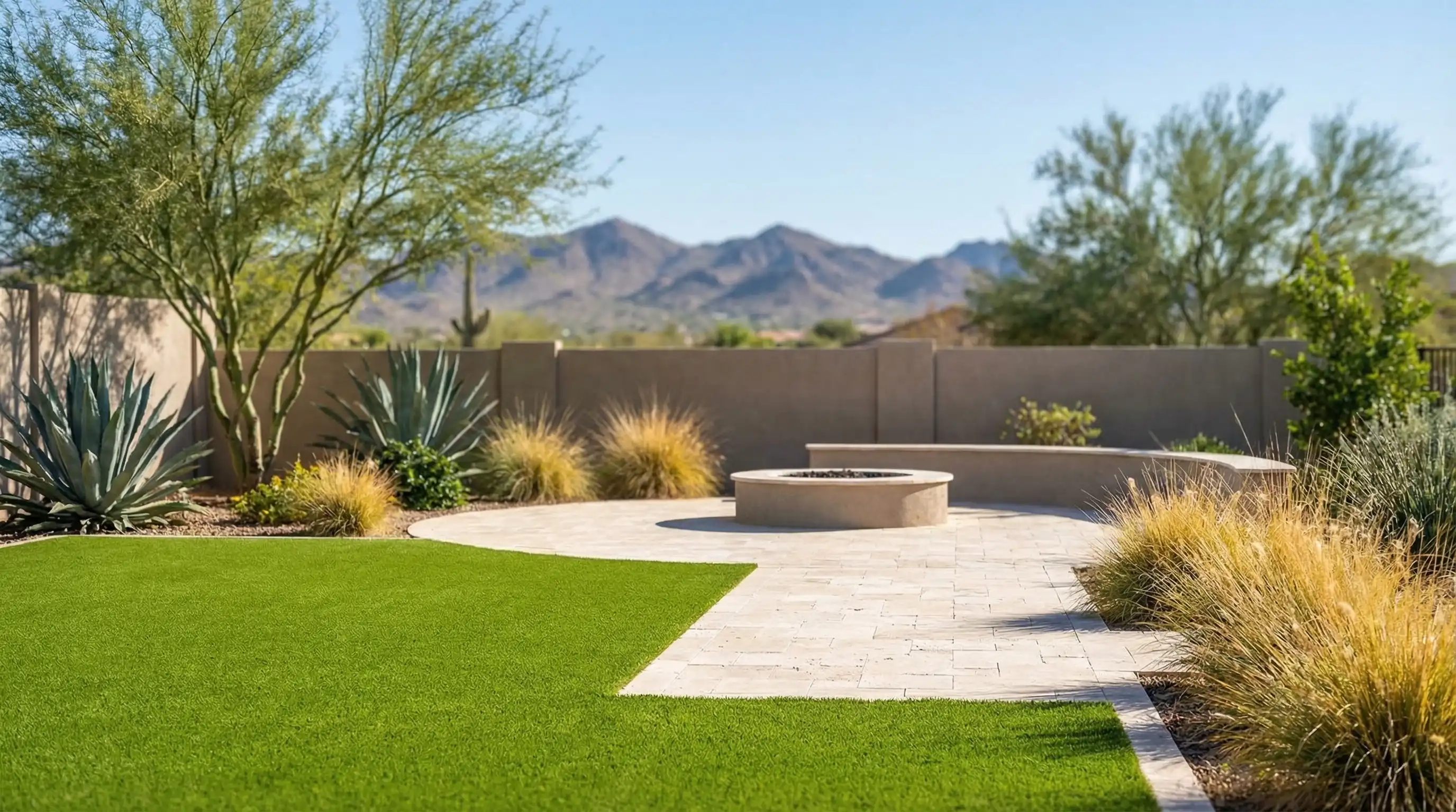 Professional pest control technician applying perimeter treatment at the foundation line of a stucco home in Mesa, AZ, with desert gravel landscaping and clear blue sky
