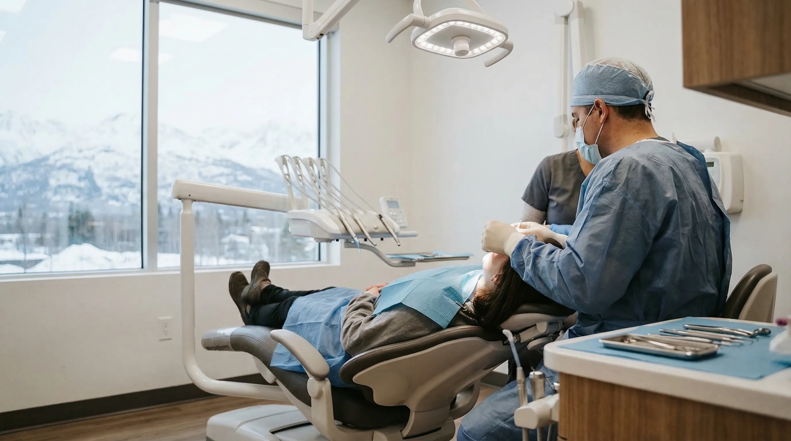 Professional dentist consulting with a patient in a modern dental office in Anchorage, AK with Chugach Mountain view