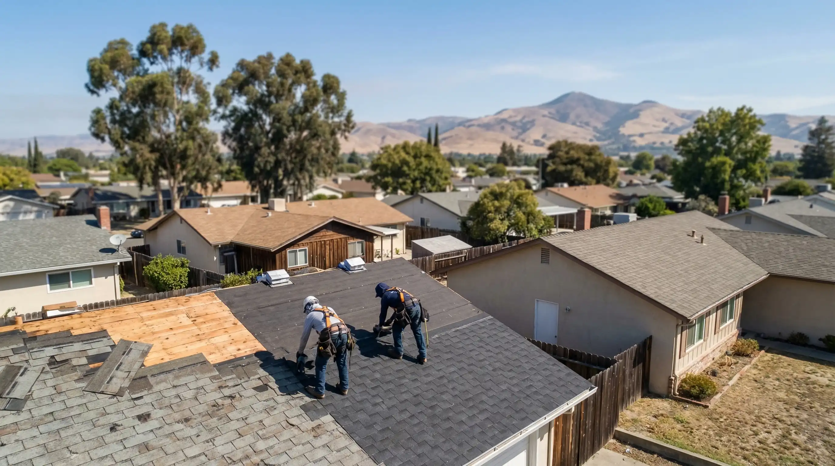 Licensed roofing contractor inspecting a composition shingle roof on a suburban ranch-style home in Fremont, CA with Mission Peak hills in the background