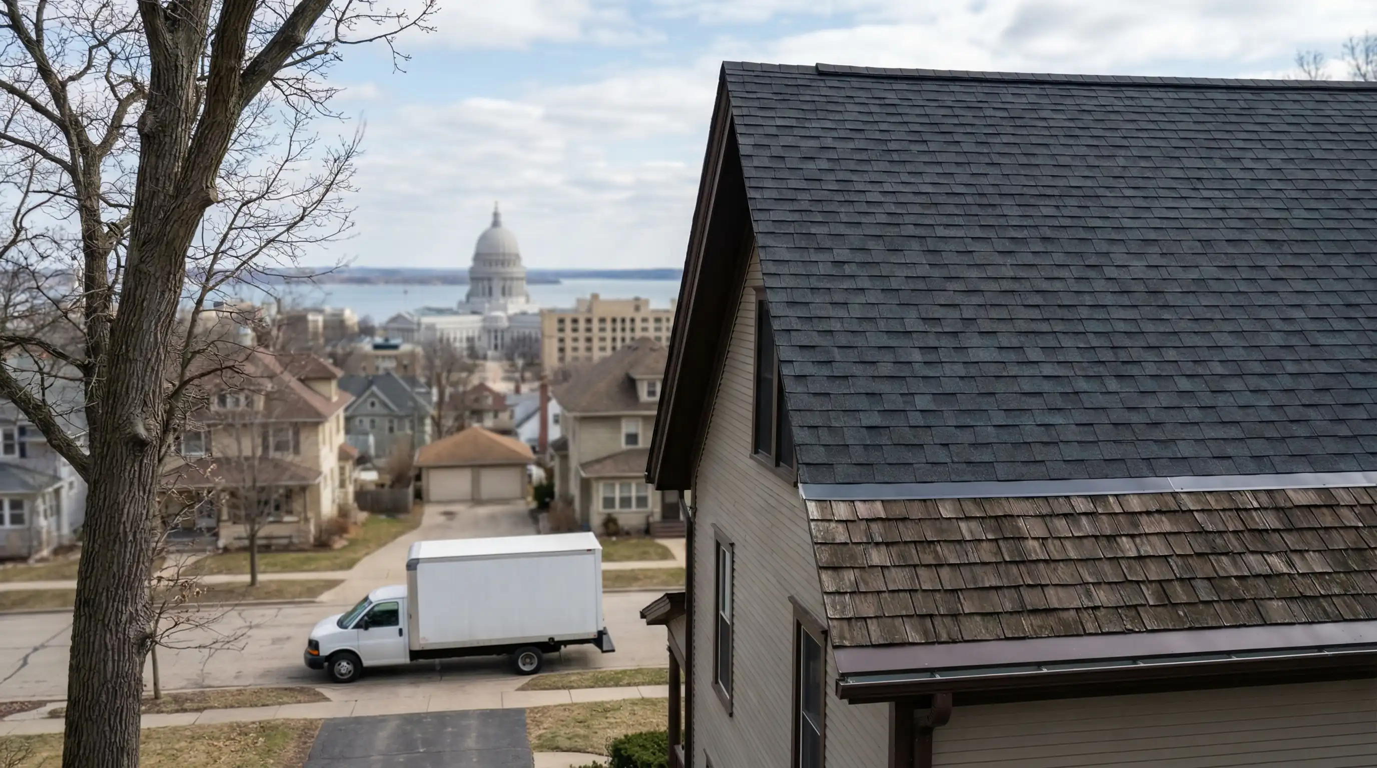 Professional roofing contractor installing architectural shingles on a residential home in Madison, WI with suburban neighborhood in background