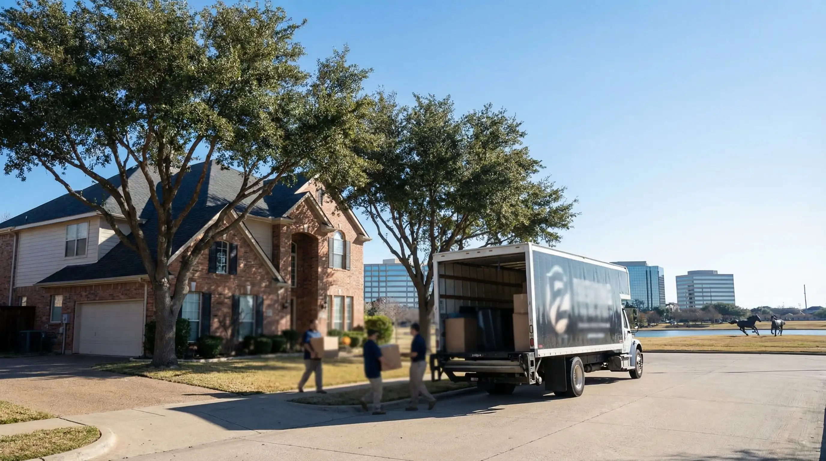 Professional moving crew loading truck in front of suburban home in Irving, TX with DFW area skyline in background