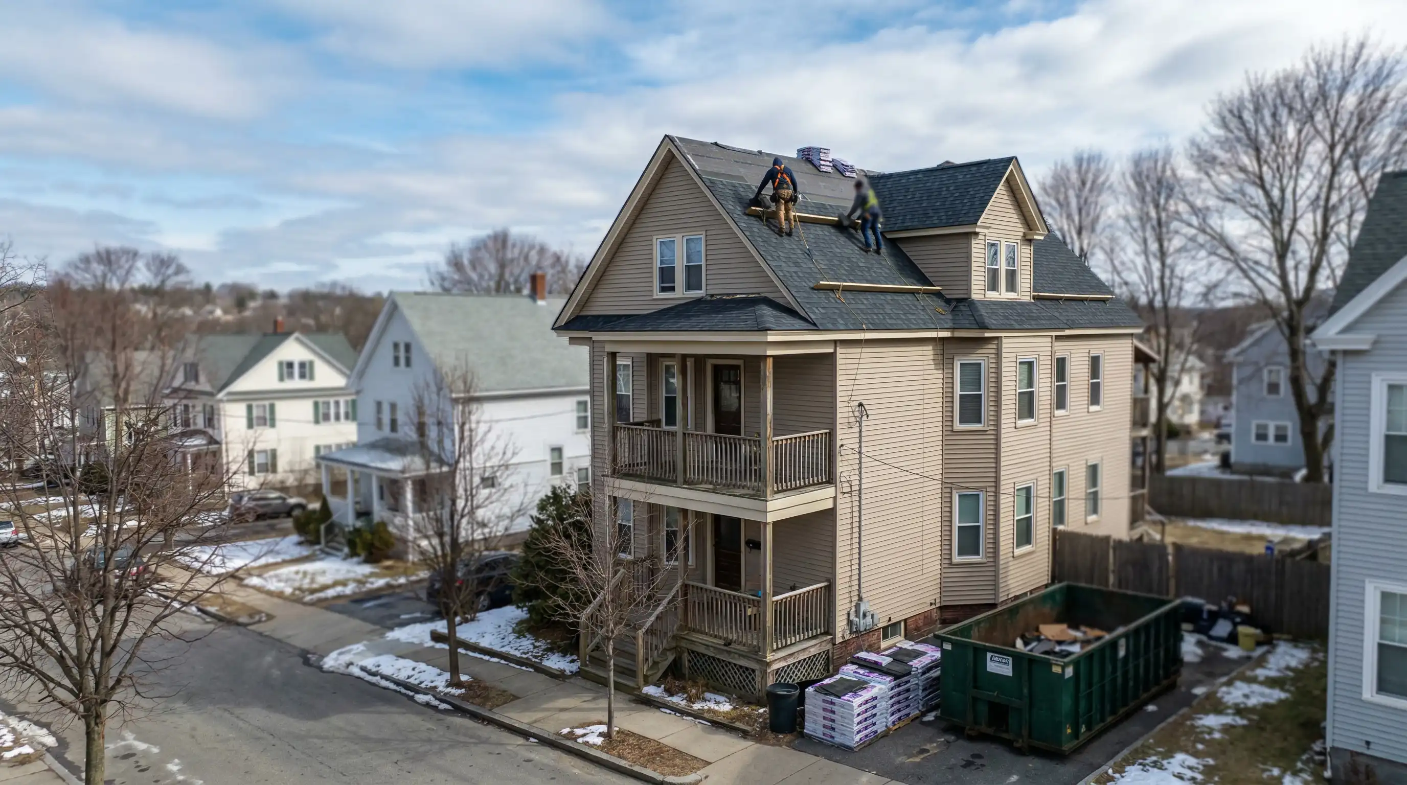 Professional roofing crew installing architectural shingles on a Worcester, MA triple-decker home