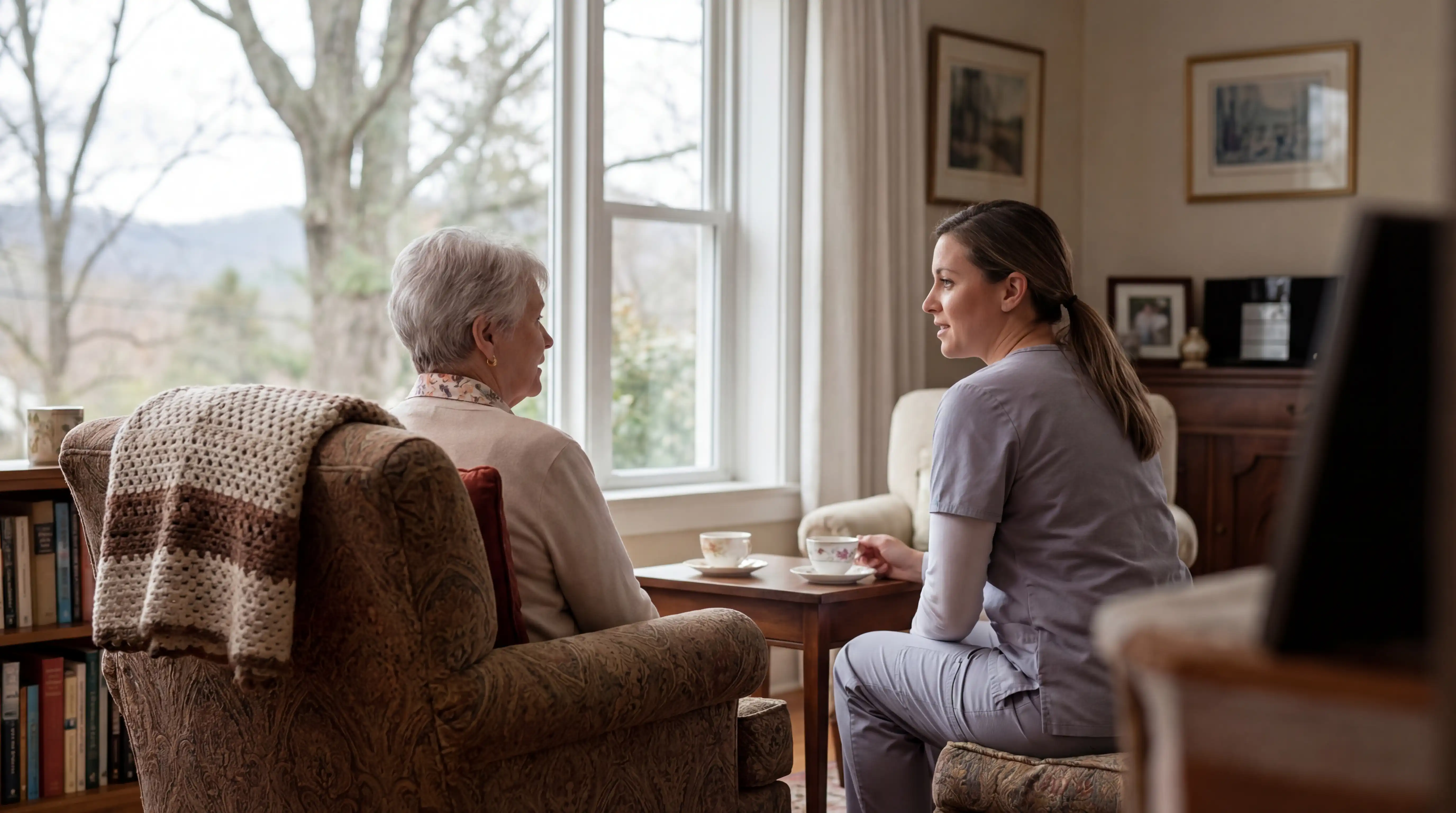 Senior care coordinator reviewing care plan with adult daughter at professional desk in West Knoxville office, Tennessee home care license certificate on wall, Knox County residential streetscape through window