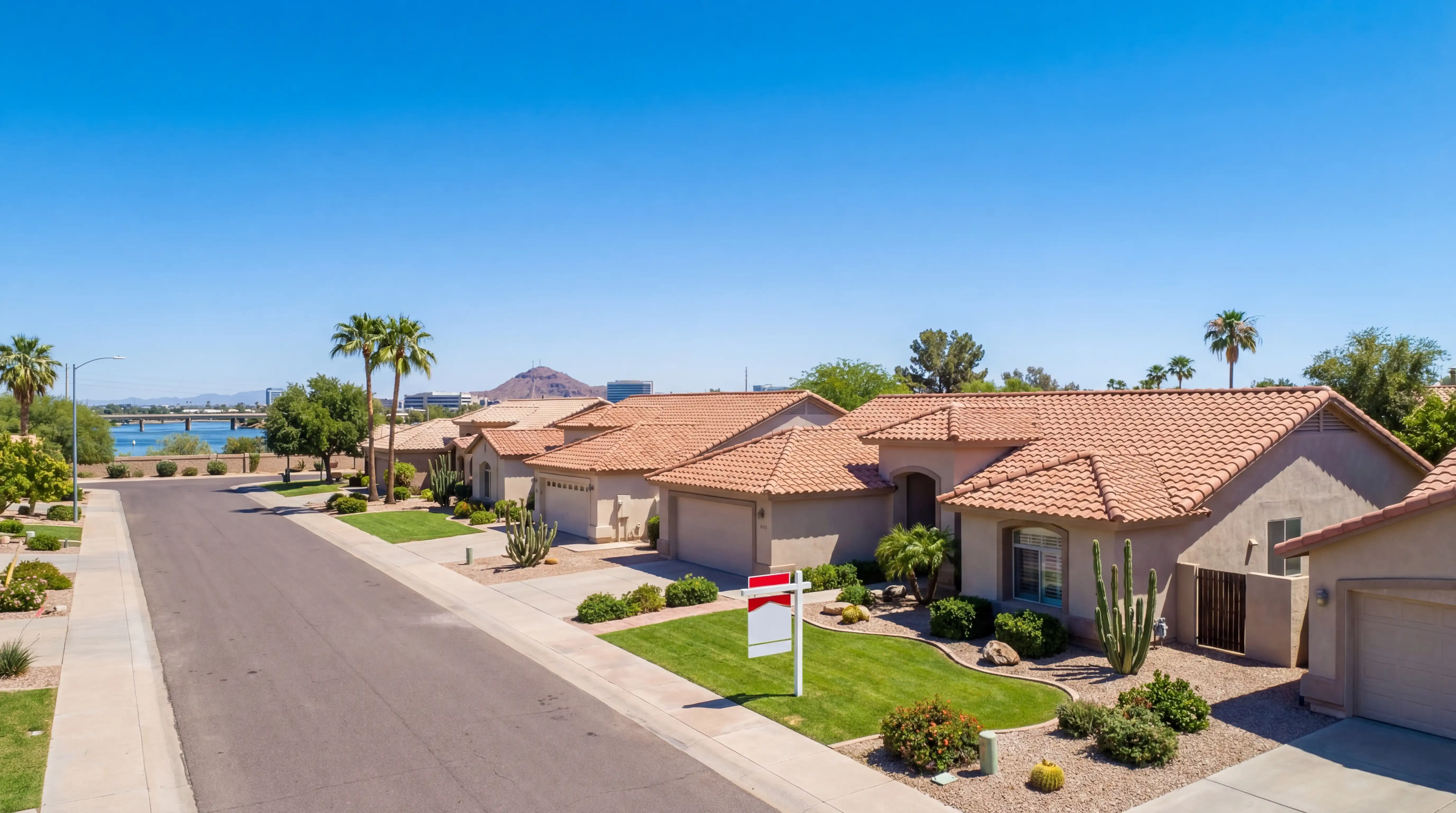 Real estate agent handing house keys to a young couple outside a stucco home in Tempe, AZ with desert landscaping