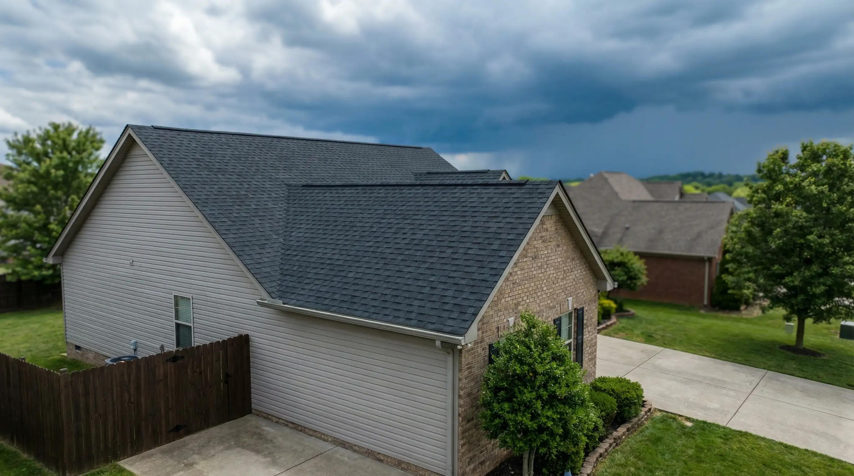 Newly installed architectural shingle roof on a brick suburban home in Murfreesboro's Barfield Crescent neighborhood with storm clouds building in the Tennessee sky