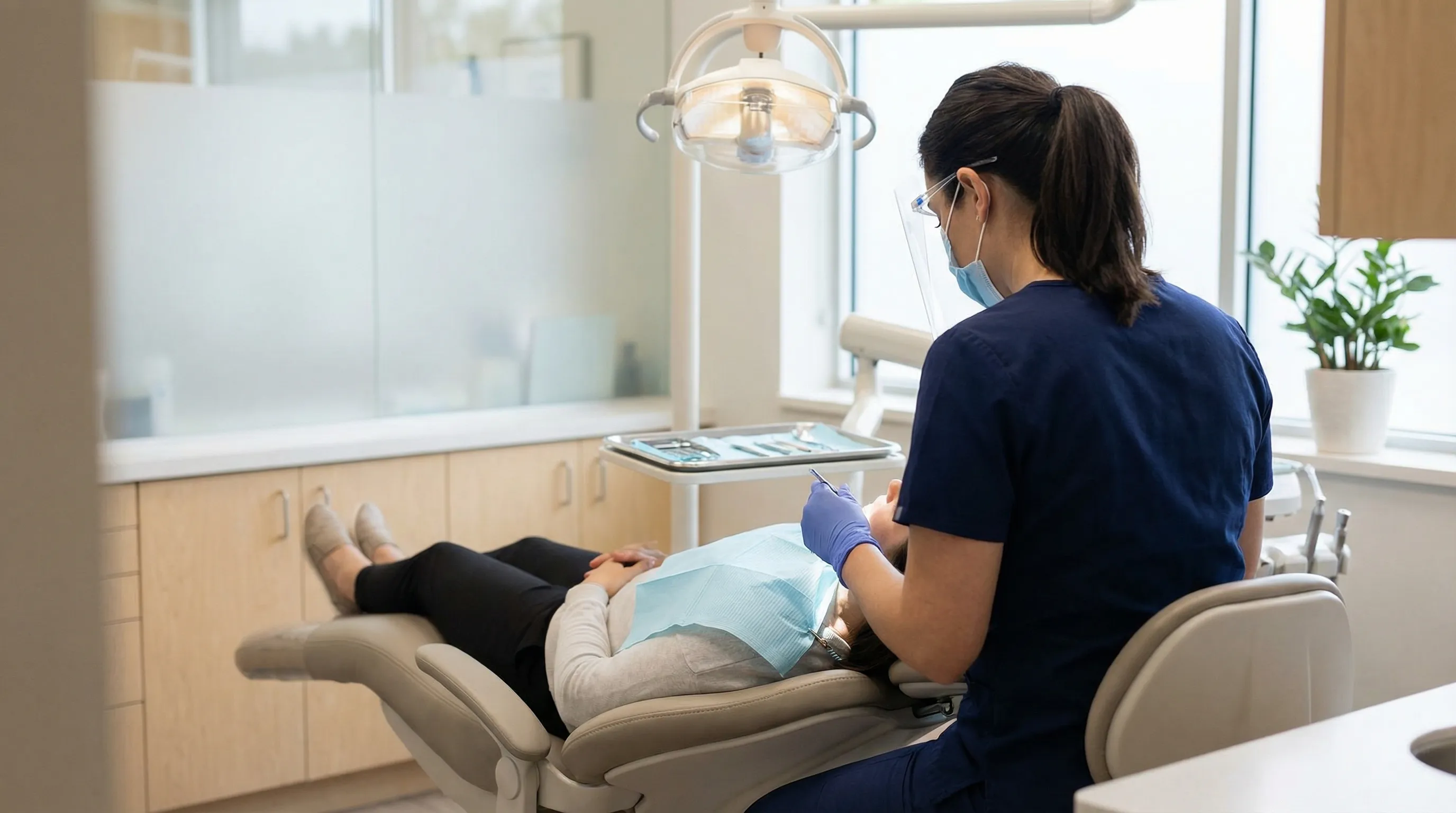 Dental hygienist in blue scrubs performing patient cleaning in a modern dental operatory at a Lancaster, CA family dental practice
