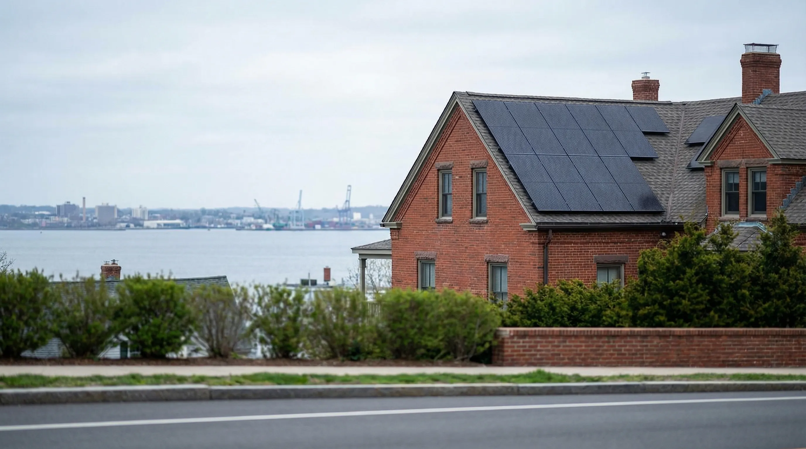 Solar panels installed on a well-maintained Bridgeport CT home rooftop with Long Island Sound visible in background on a clear day