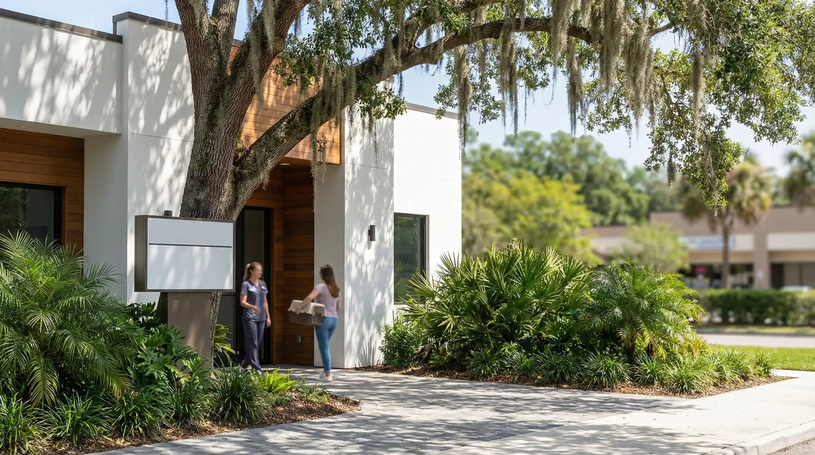 Professional veterinary clinic exterior in Gainesville, FL with live oak canopy and a vet technician greeting a patient at the entrance