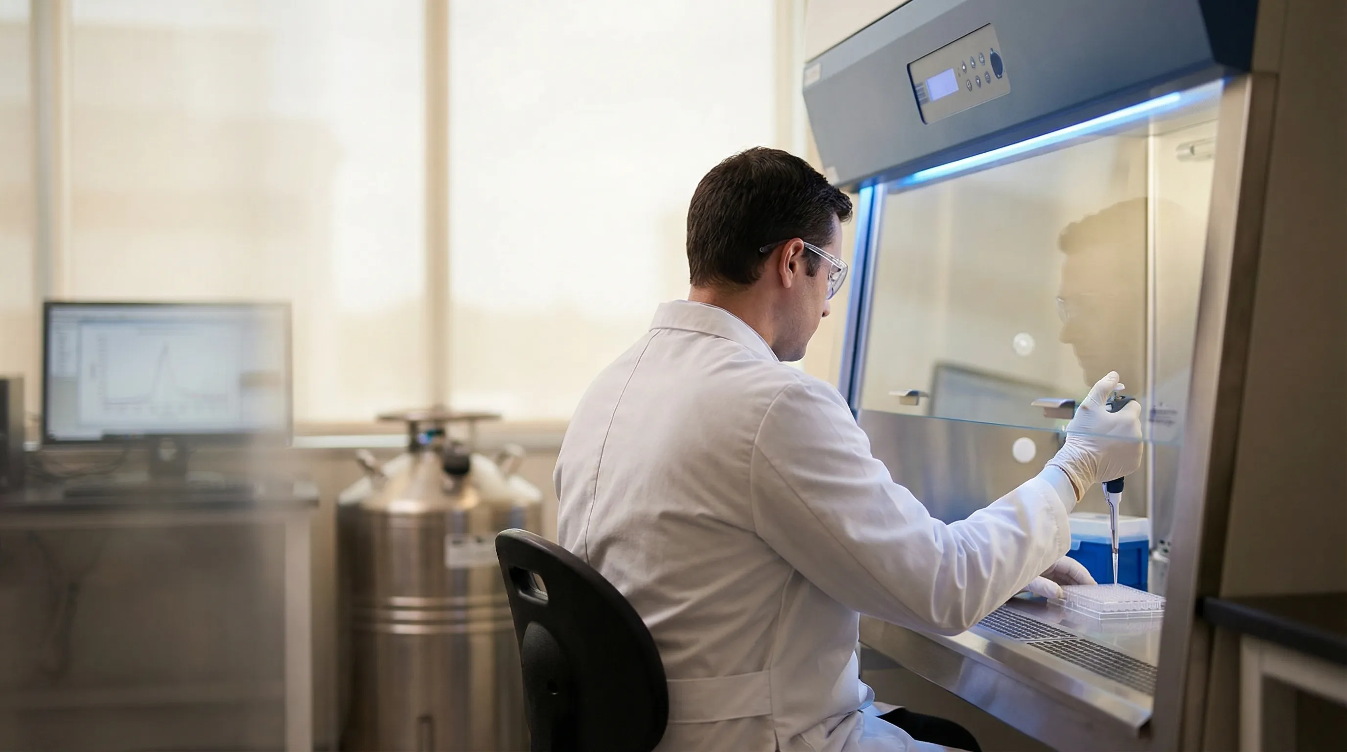 Life sciences researcher working at biosafety cabinet in a modern New Haven biotech laboratory at Yale Science Park
