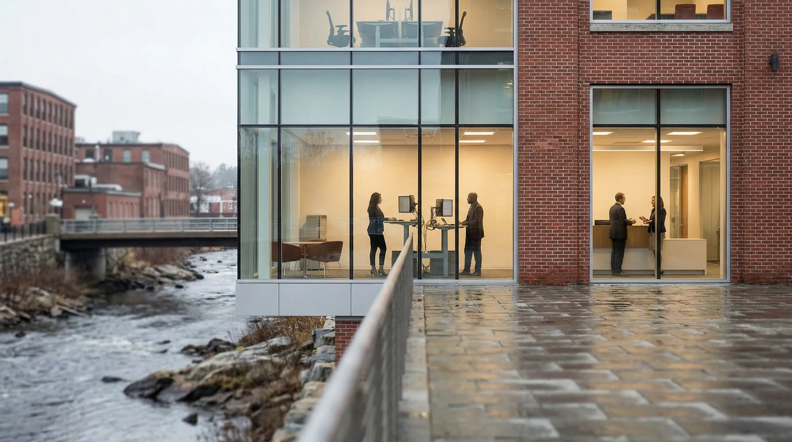 IT technician monitoring network security dashboards in a Manchester, NH business office with servers and dual screens visible