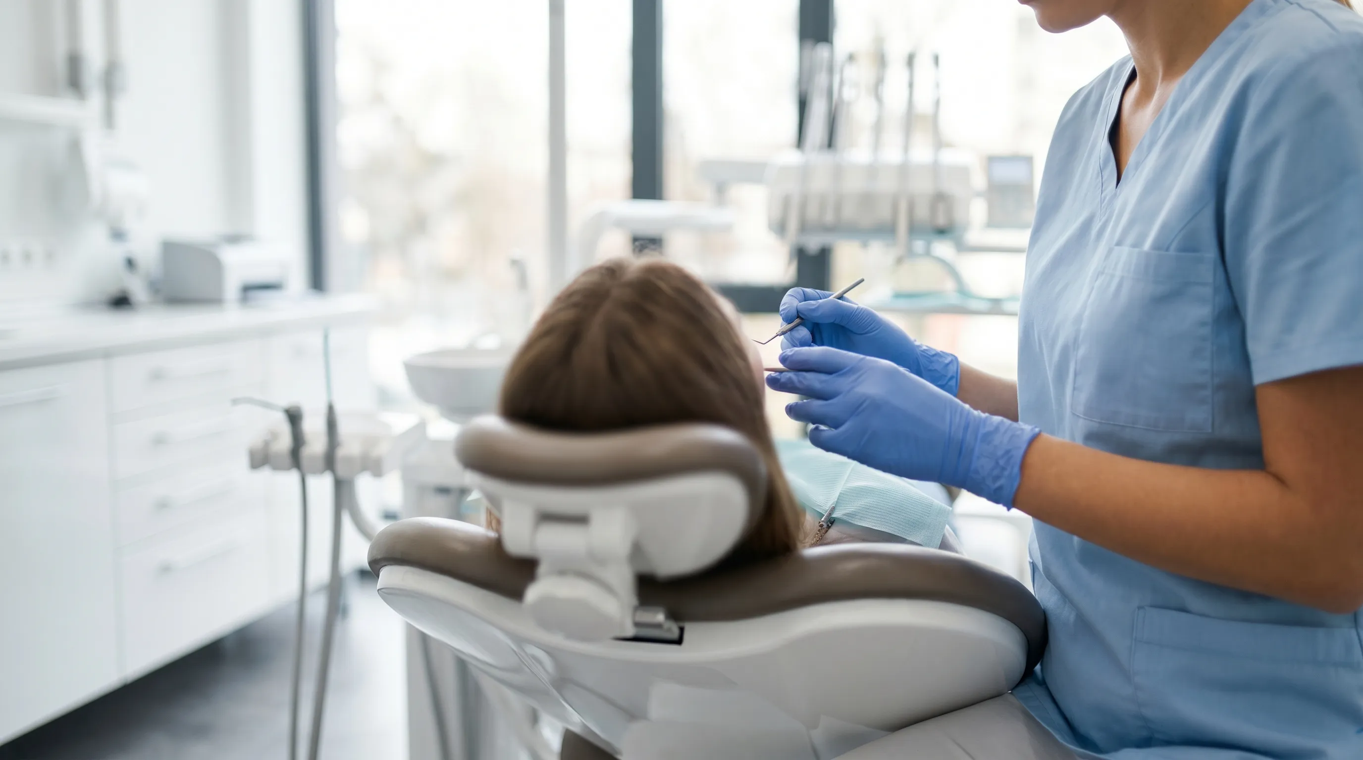 Professional dental hygienist in scrubs examining a patient in a modern dental treatment room at a Kenosha, WI dental practice