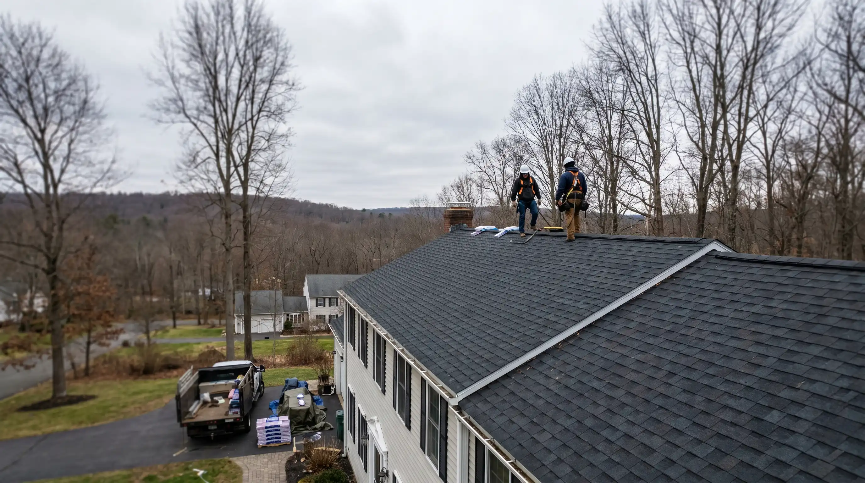 Professional roofing crew installing dark asphalt shingles on a two-story colonial home in Danbury, CT