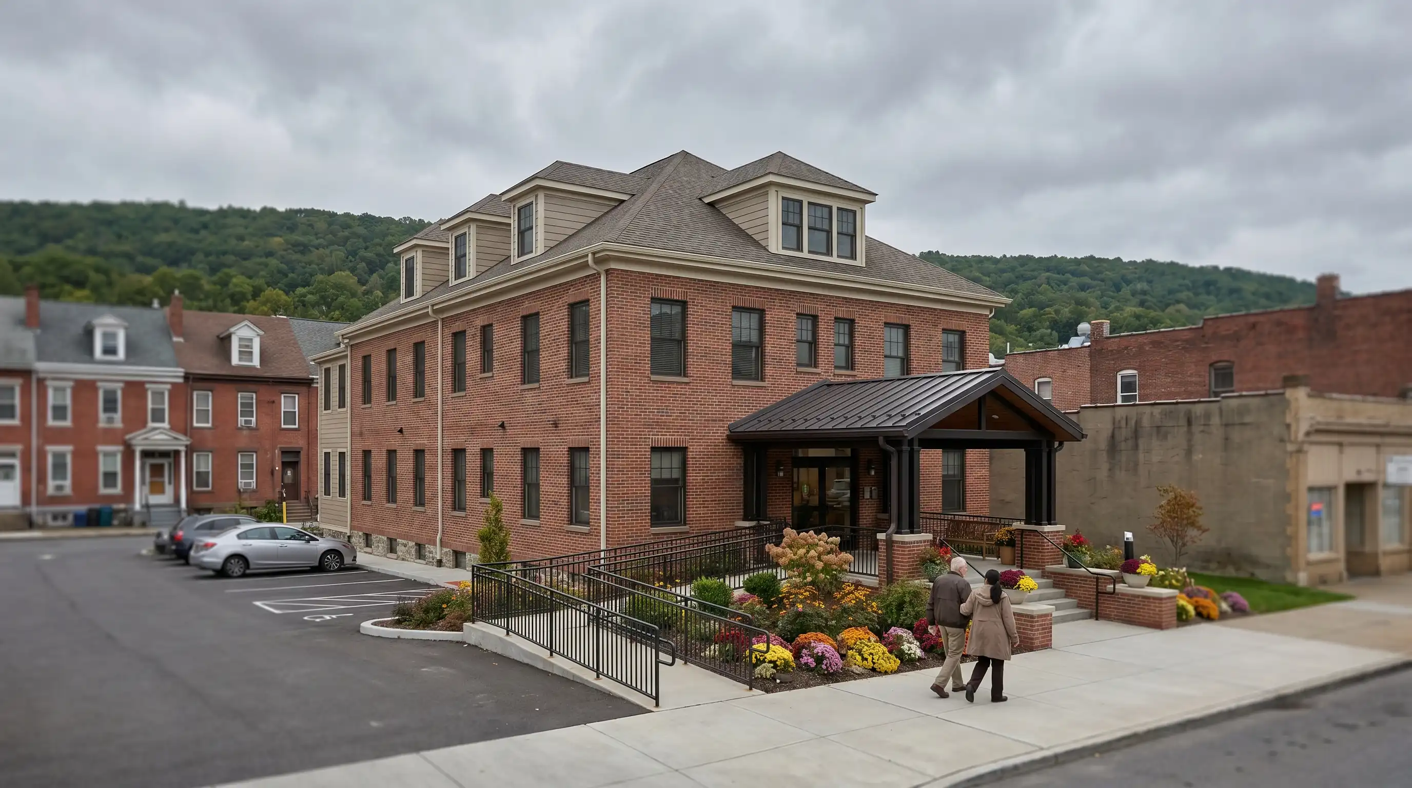 Caregiver and elderly resident walking together through the entrance of a brick senior care facility in Scranton, PA on a calm overcast afternoon