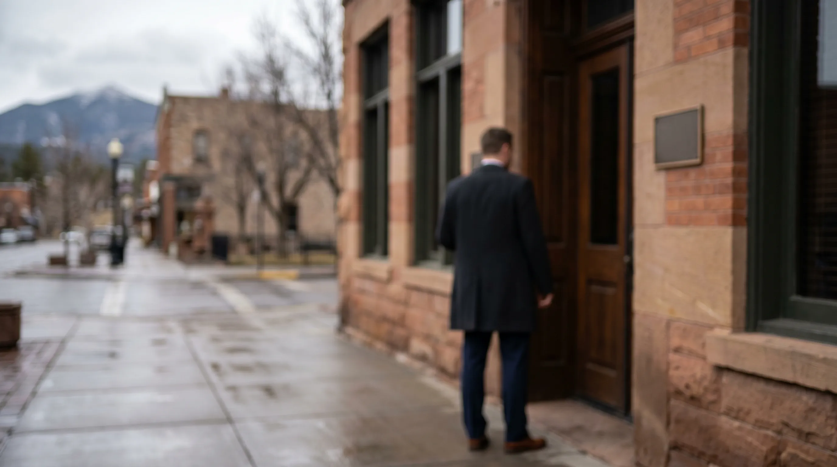 Personal injury attorney reviewing case documents in a professional Flagstaff law office with Route 66 and downtown Flagstaff visible through the window