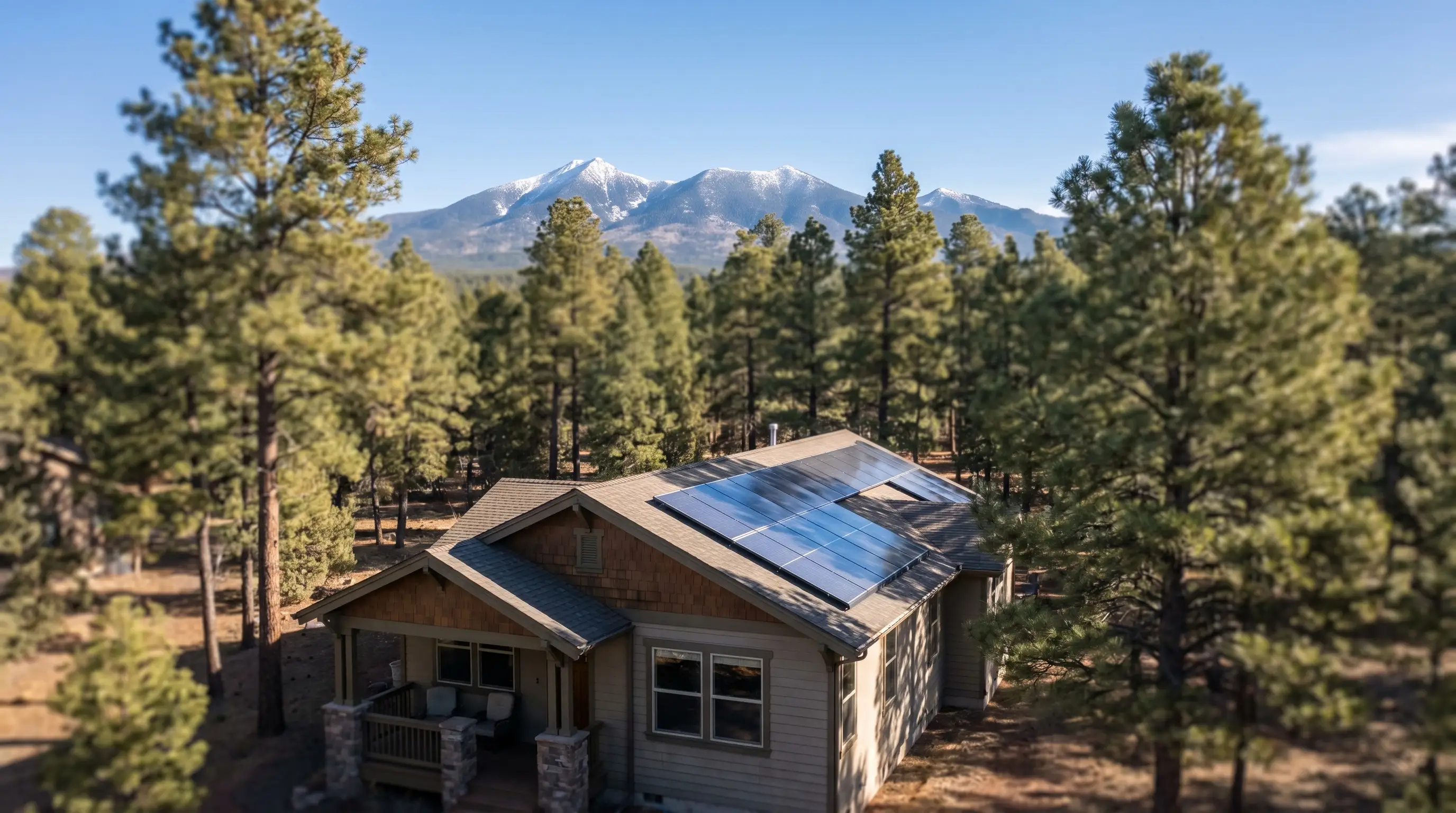 Solar installer securing panels on a residential Flagstaff rooftop with ponderosa pines and San Francisco Peaks visible in the background under clear blue sky