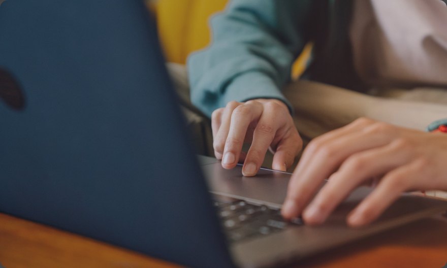 Close-up of hands typing on a laptop while drafting messaging