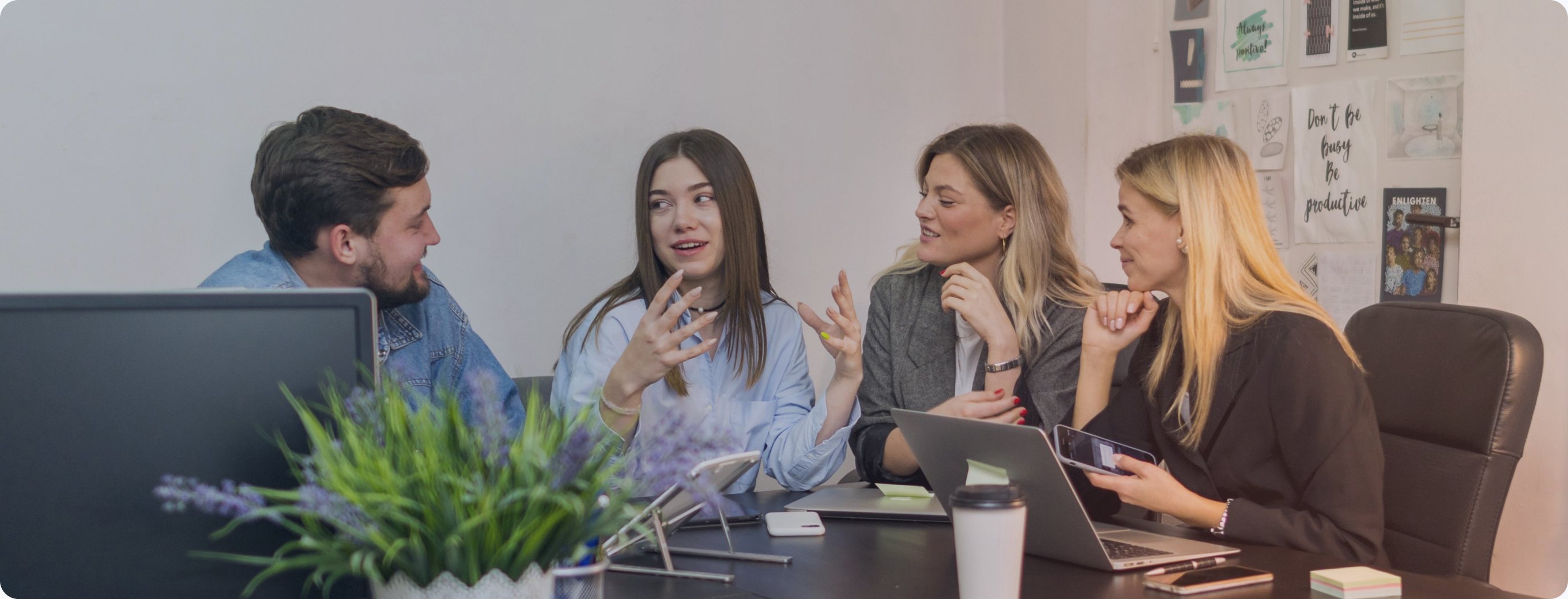 Four colleagues talking around a desk in an open office