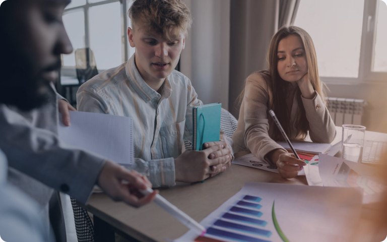 Colleagues reviewing printed charts across a meeting table