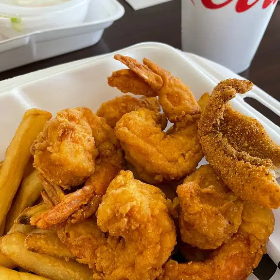 A basket of fried shrimp and french fries.