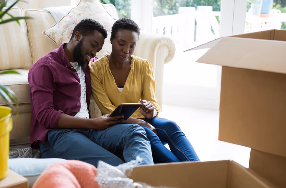 Couple at home looking at a tablet while unpacking boxes