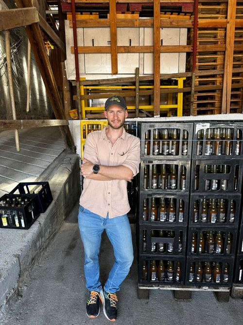 Der Gründer Dominik Becker lehnt an einer Palette von The Pure Brew im Lager in Stuttgart.