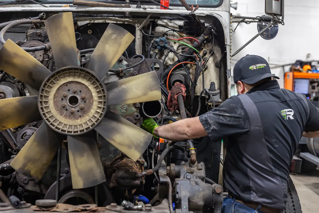 Technician performs heavy-duty engine repair on an exposed truck engine.