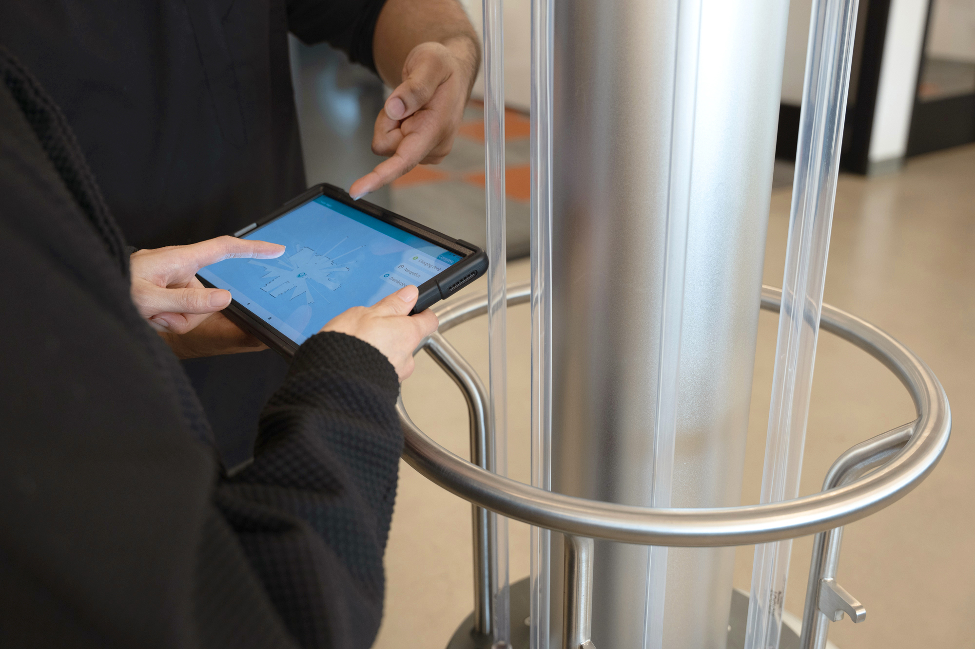 A robotics expert training someone how to use a tablet to control a UVC robot