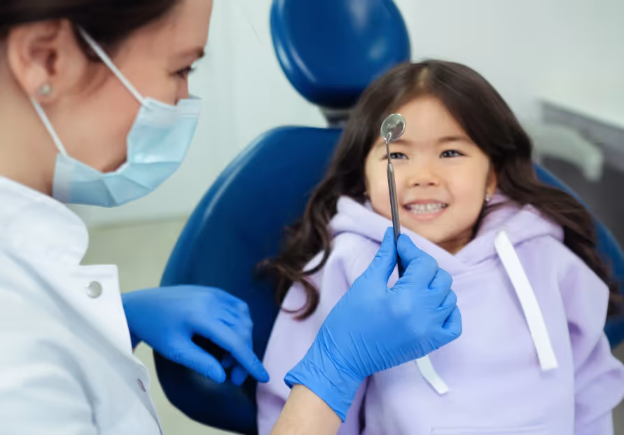 Child smiling at dental mirror
