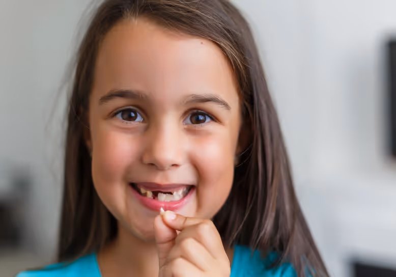 Young girl holding lost tooth 