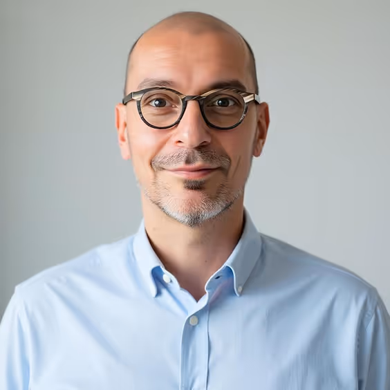 Bald professional in glasses and blue shirt smiling at camera