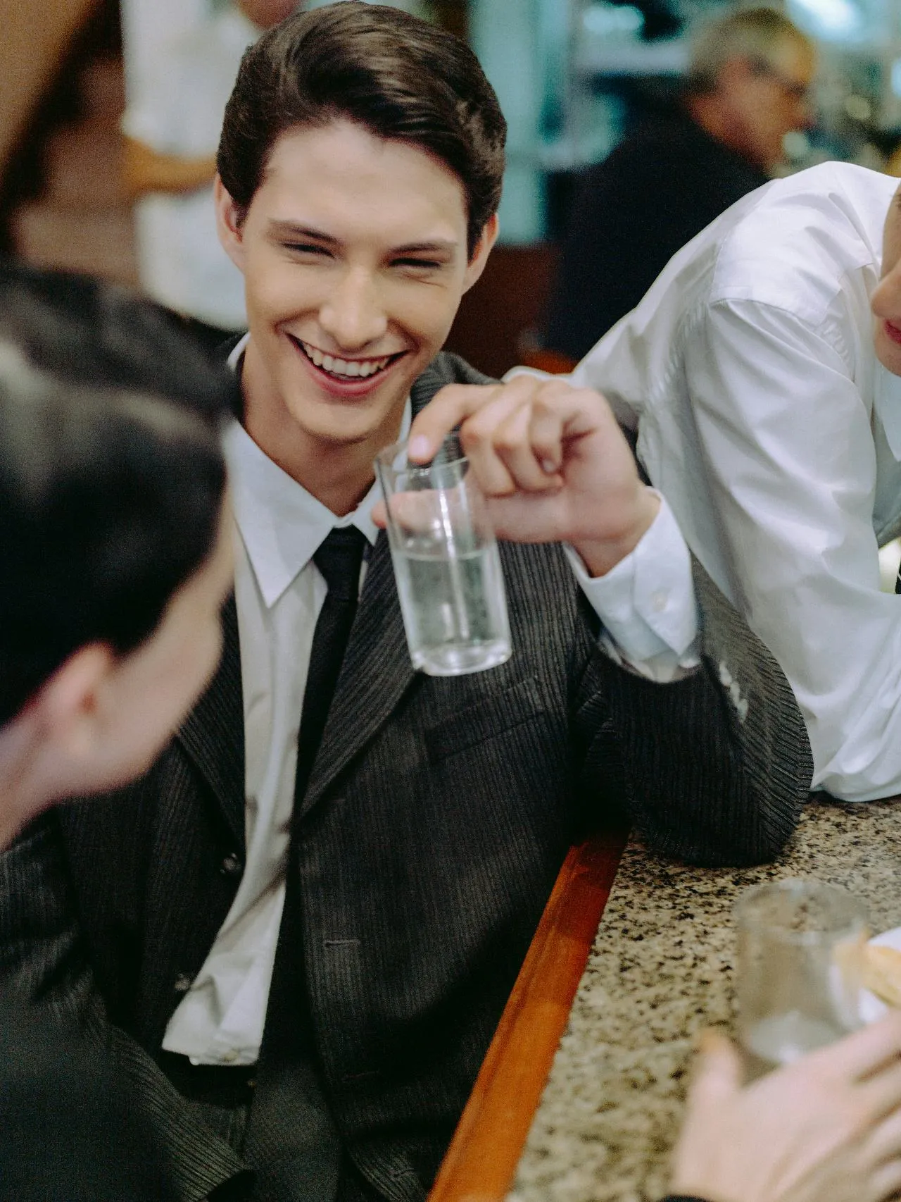 Smiling man in a business suit surrounded by people in conversation
