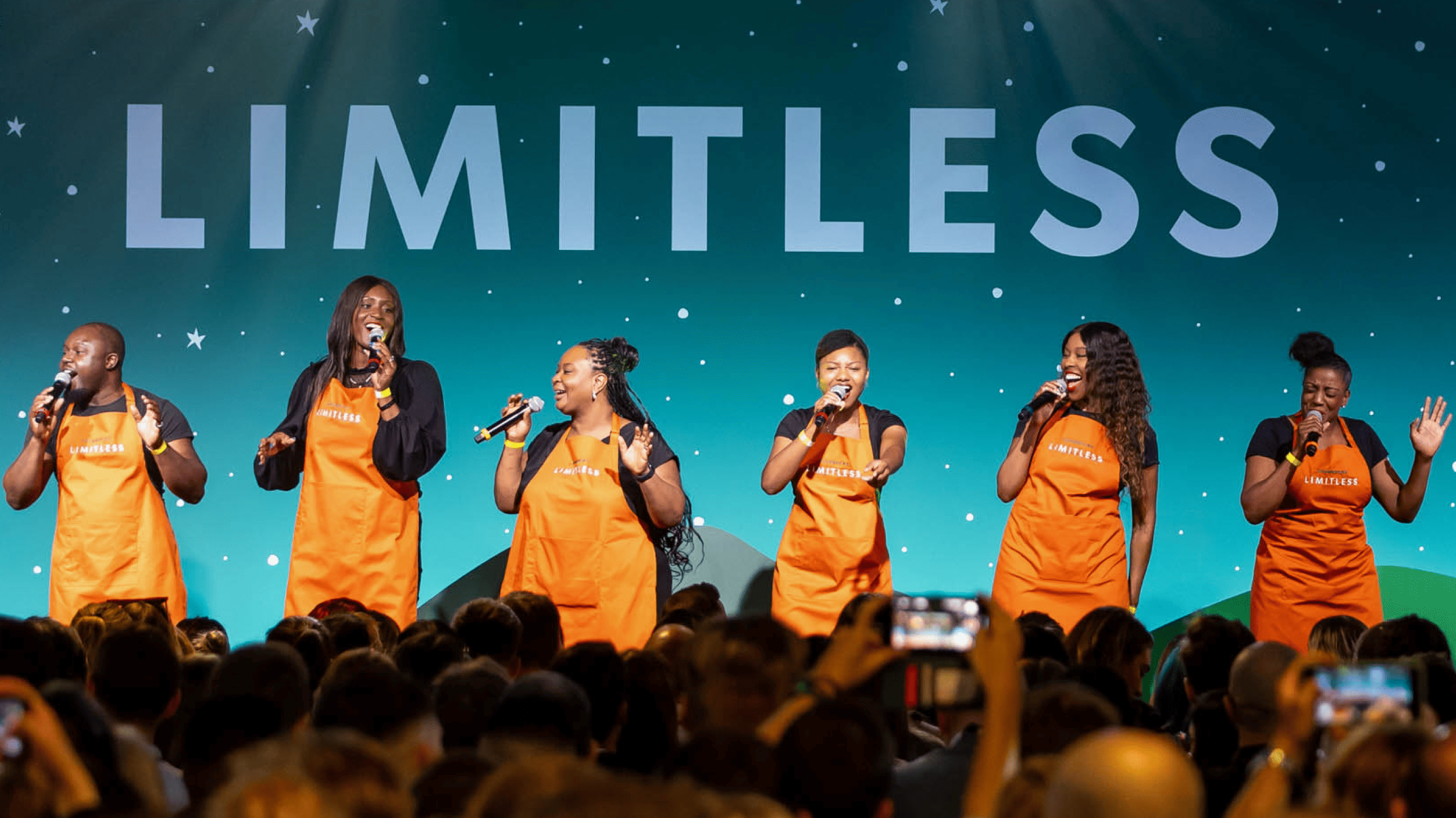Diverse group of people on a stage wearing orange shirts at the Limitless Conference