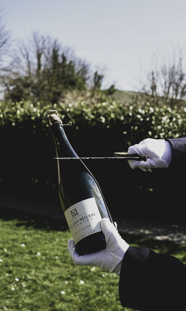 Personne effectuant un sabrage de bouteille de Champagne