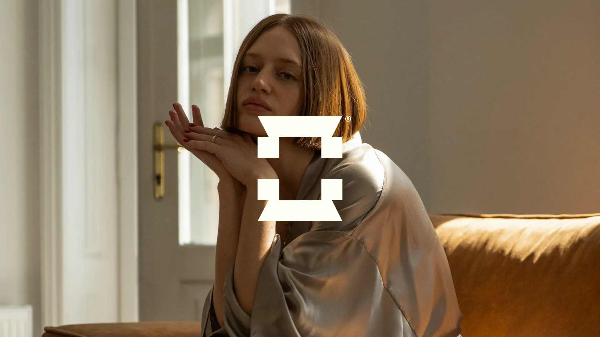 Female model sitting on a couch as a background element for Celadon Imagery's brand identity.